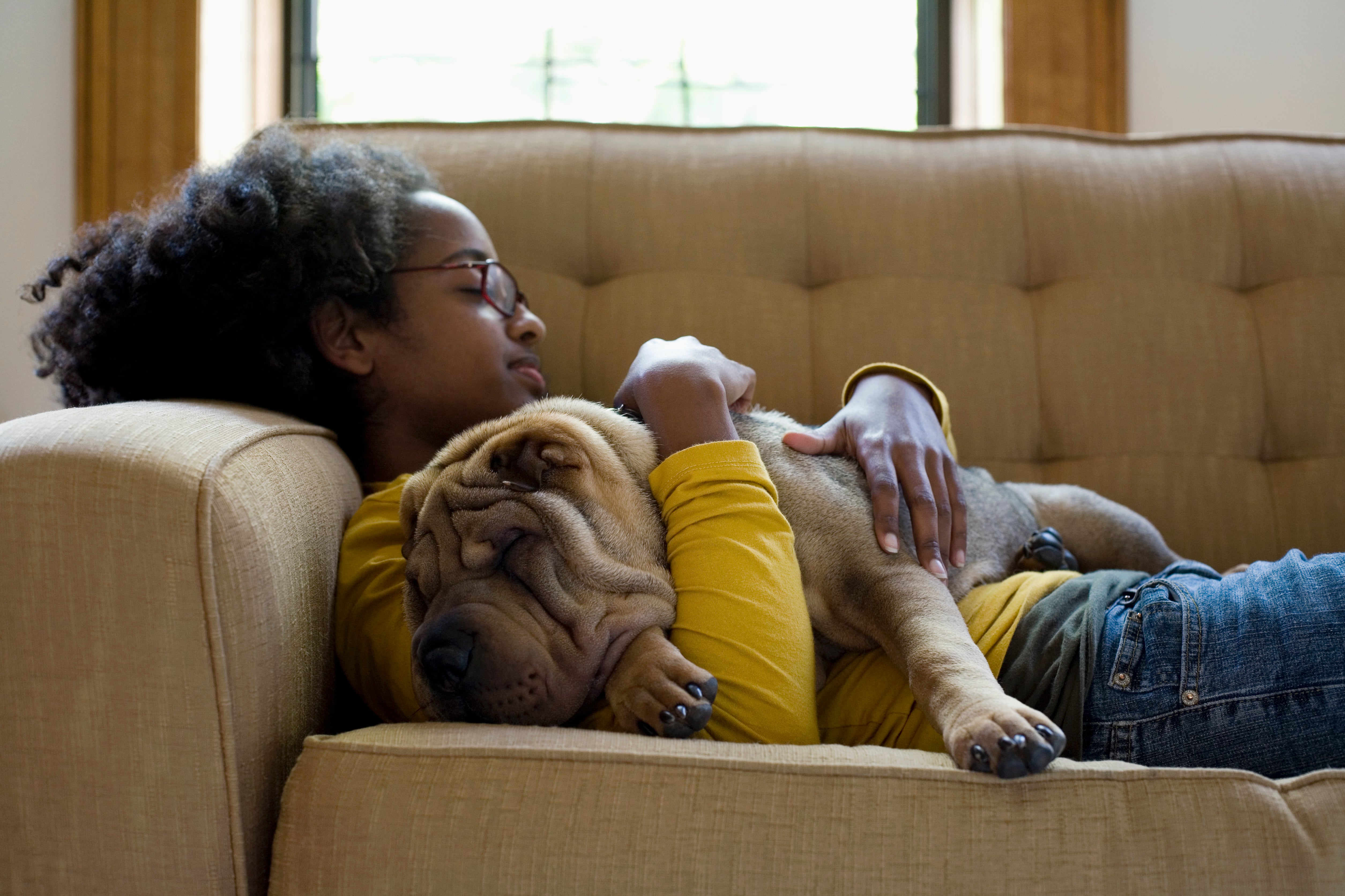 Young woman on couch with Chinese Shar-Pei dog