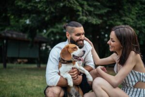 Beagle being hugged by a man and woman in the yard. people